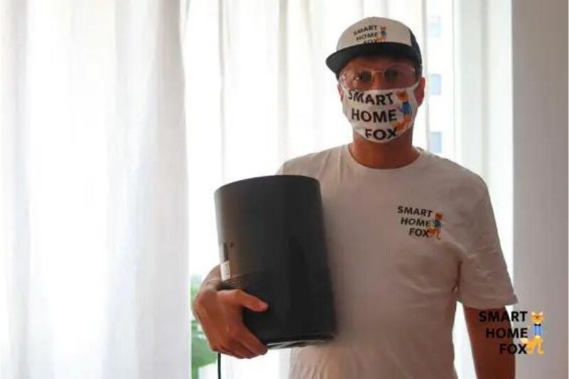 Человек держит в руке очиститель воздуха и надевает респираторную маску